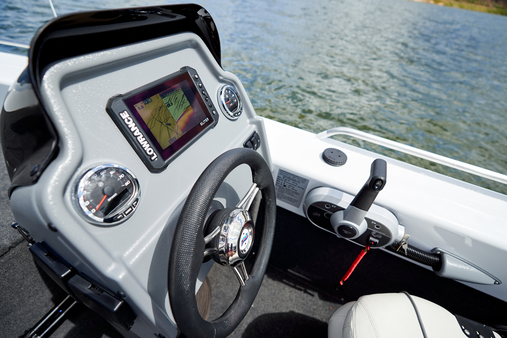 Close-up of a boat helm featuring a Lowrance navigation screen, steering wheel, throttle control, and digital gauges.