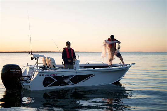 Two men fishing from a white Quintrex Territory Legend boat on calm water at sunrise.